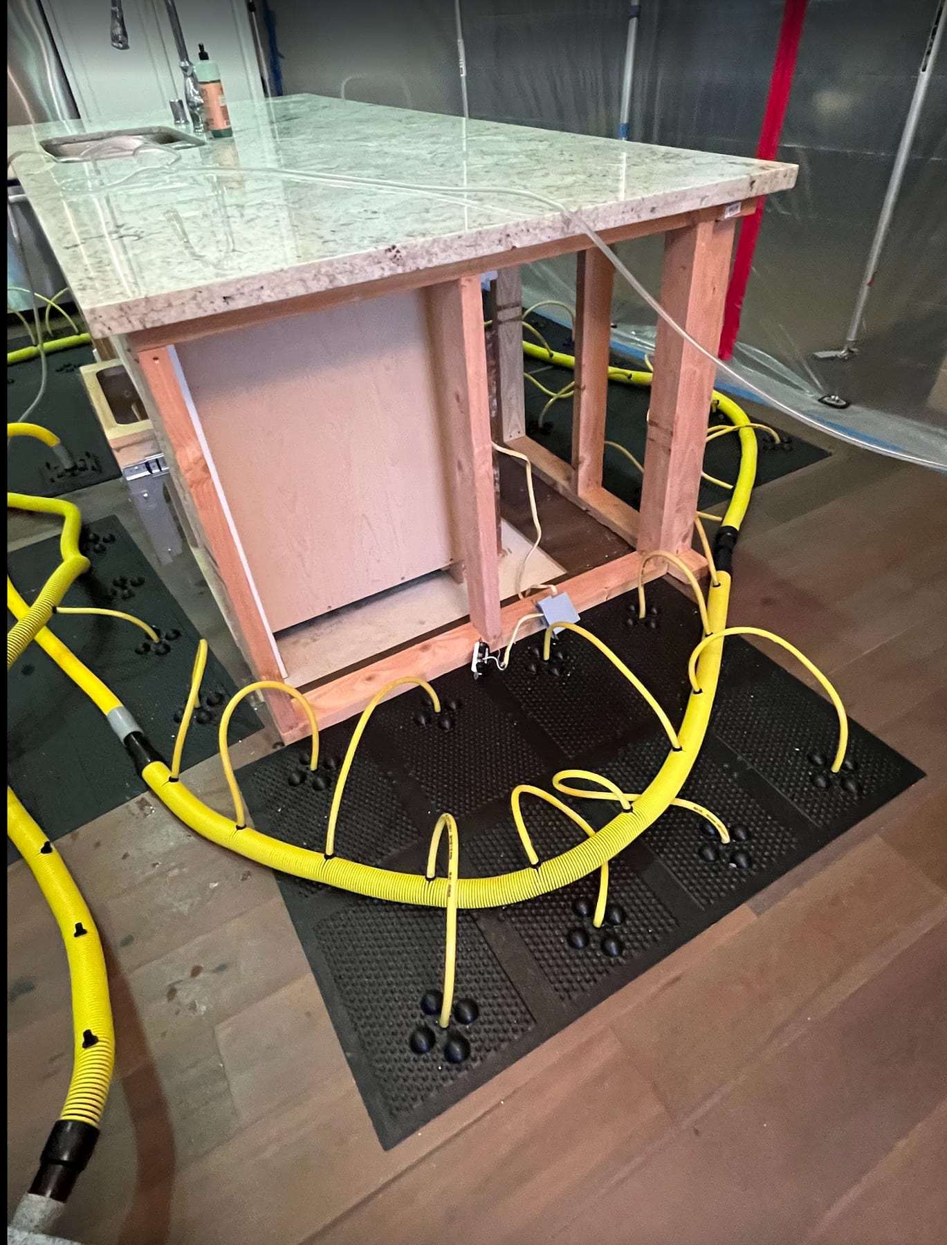 Drying mats and hoses on the floor around a kitchen island frame