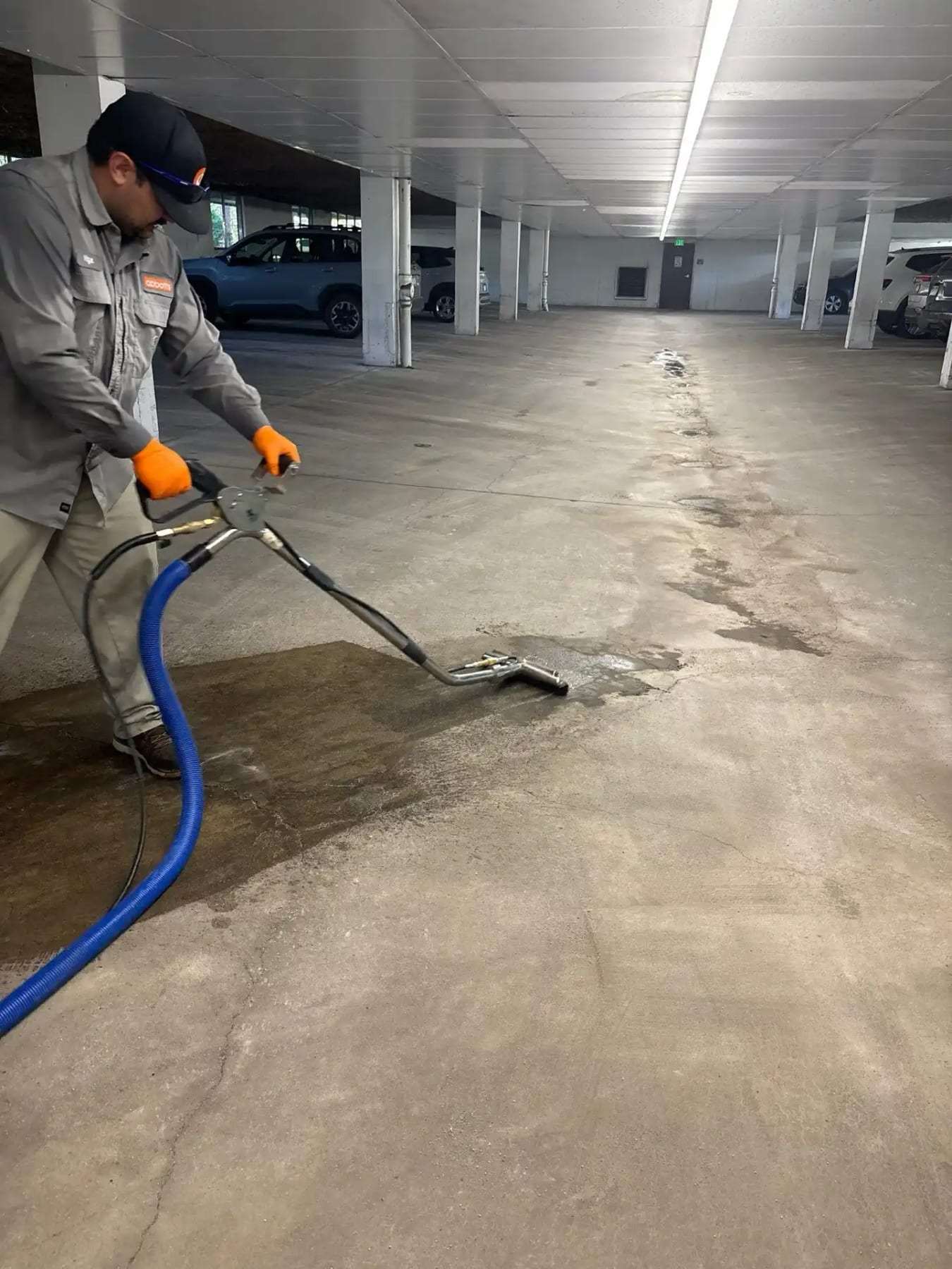 Technician extracting water from the floor of a parking garage