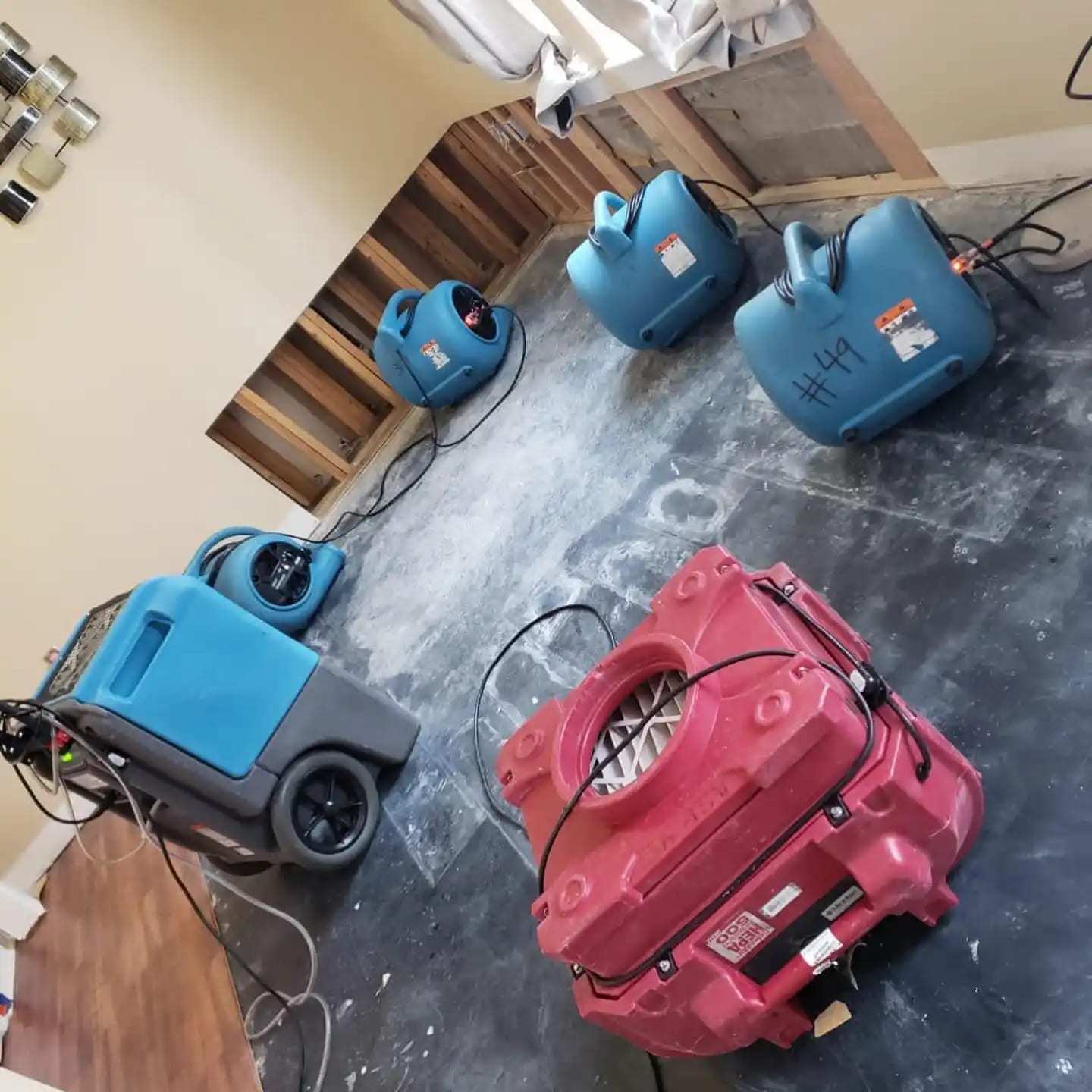 Air movers and dehumidifiers seen from above on a bare subfloor