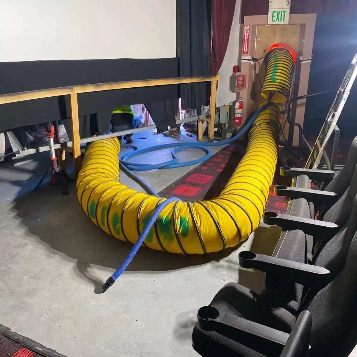 Lay-flat drying ducting run across the floor of a small theater