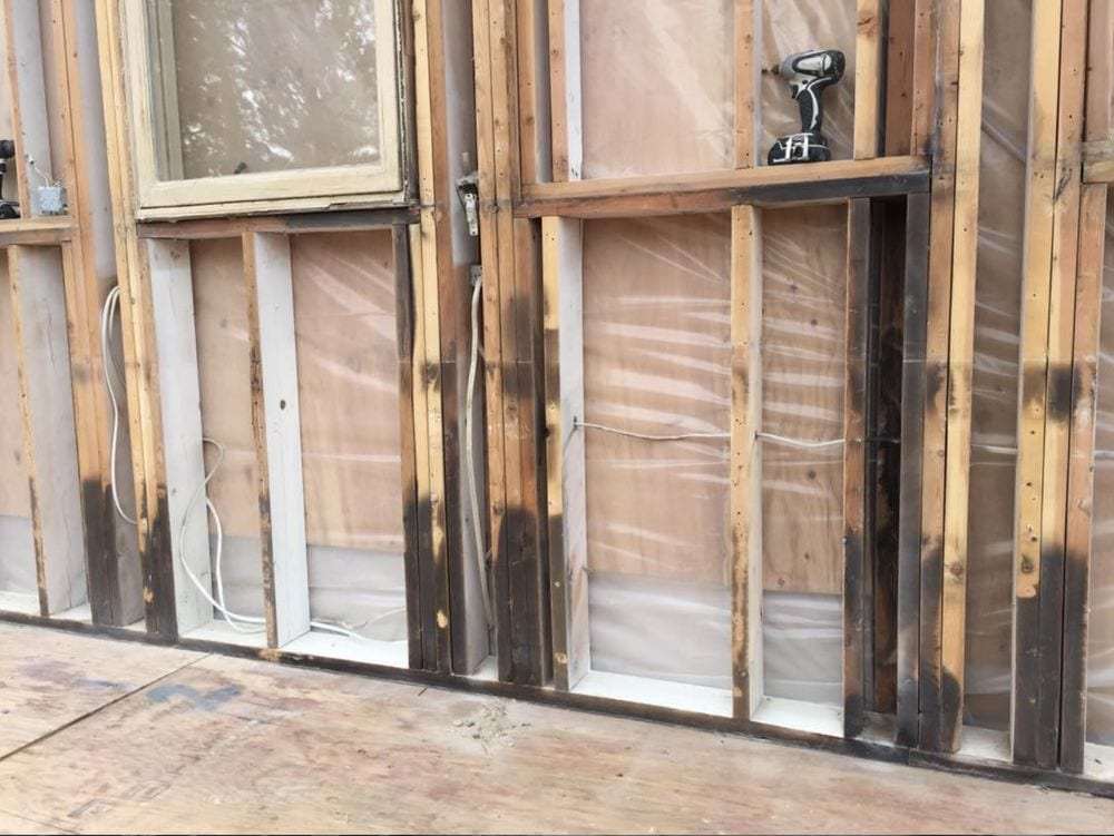 Wall stripped to the studs after water and fire damage, showing stained framing