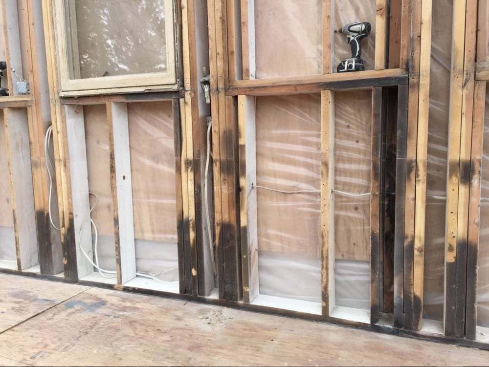 Wall stripped to the studs after water and fire damage, showing stained framing