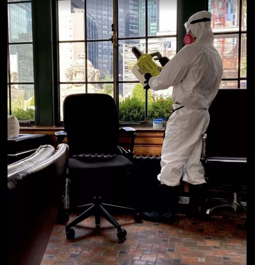 Technician in a protective suit fogging an office to treat odor