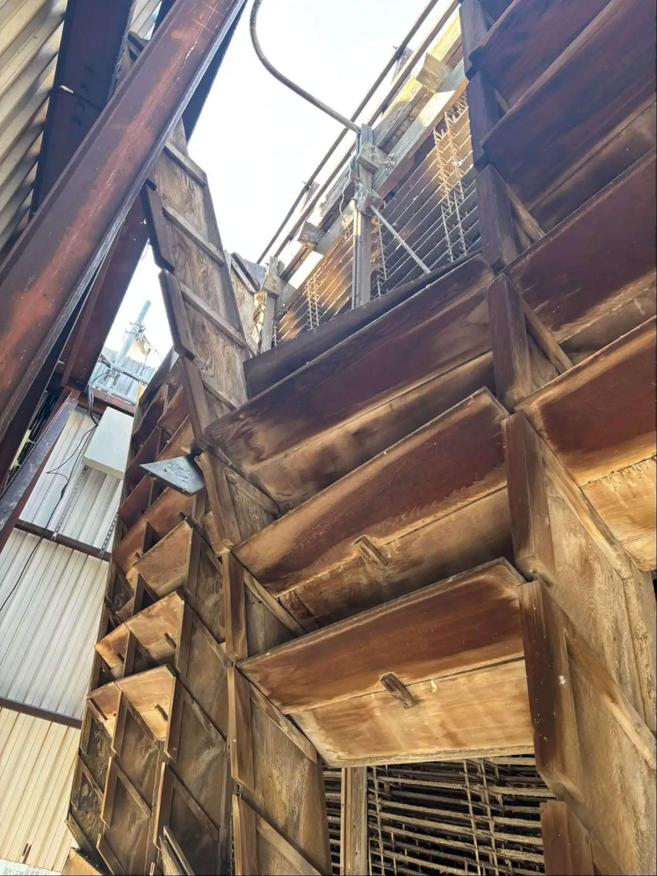 Fire-damaged roof framing seen from below with daylight through the roof