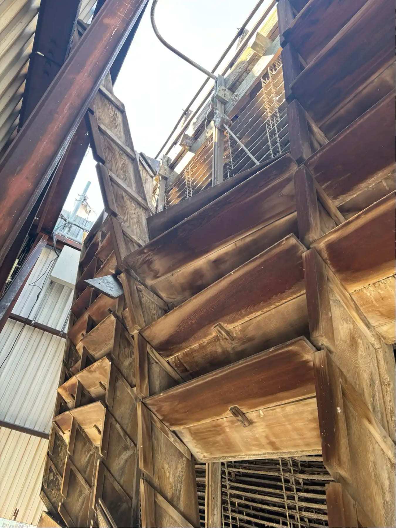 Fire-damaged roof framing seen from below with daylight through the roof