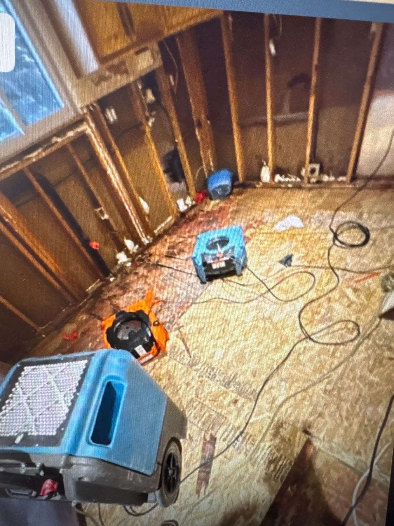 Room gutted to the framing with drying equipment and debris on the floor
