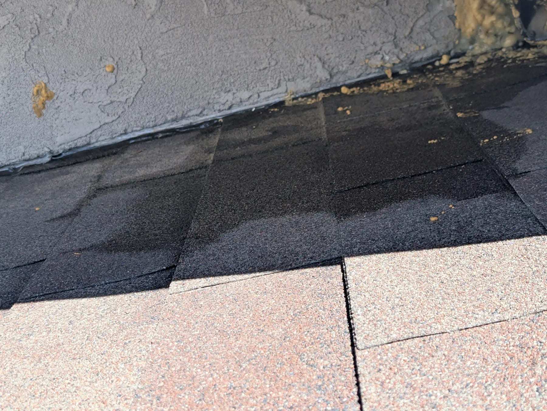 Low-slope roof with gravel debris against a stucco parapet