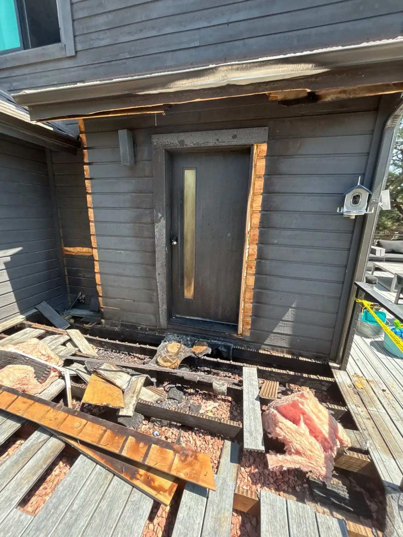 Deck boards removed at an exterior door to expose rotted framing