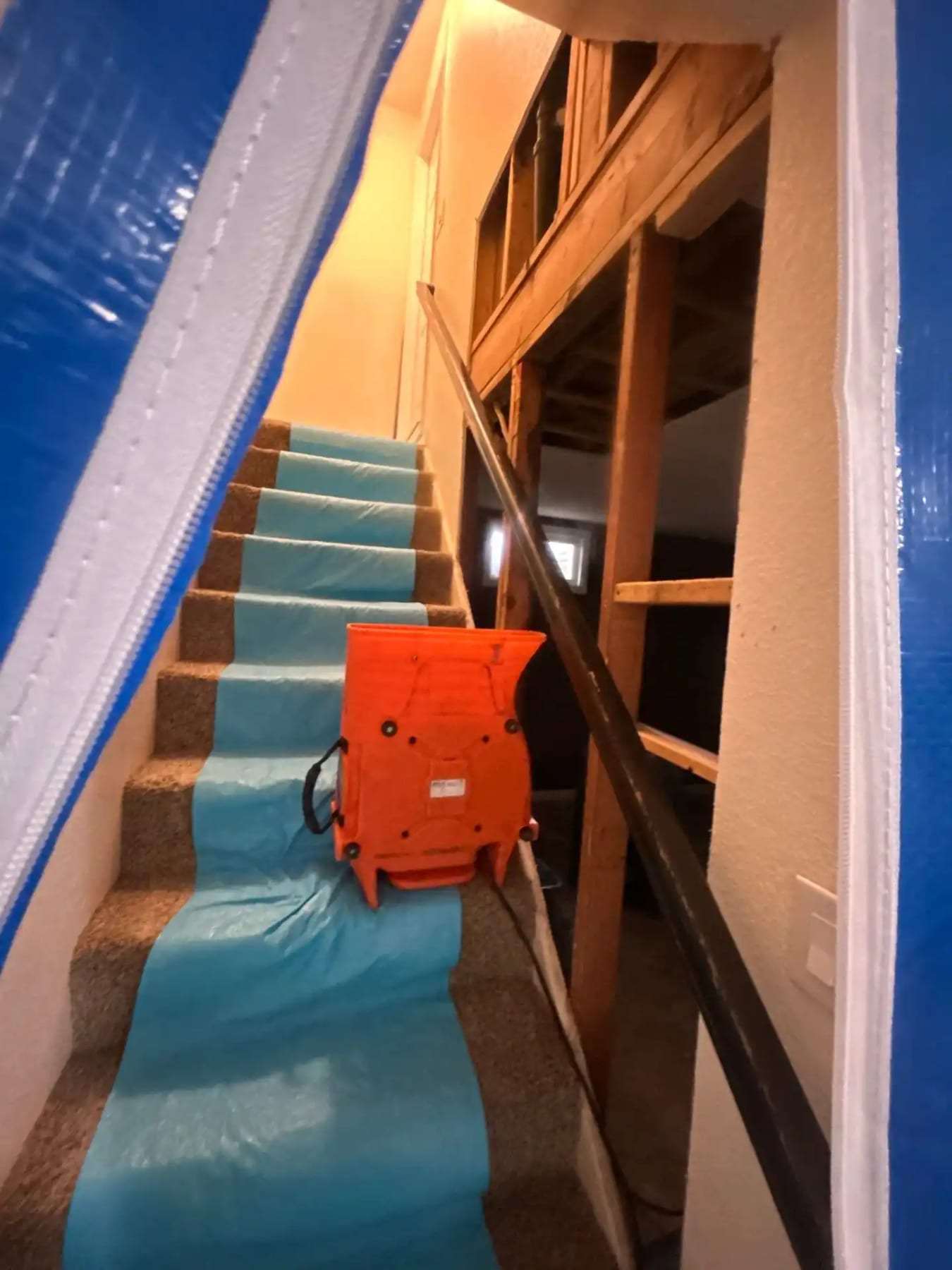 Carpeted staircase wrapped in plastic with an air mover on the steps