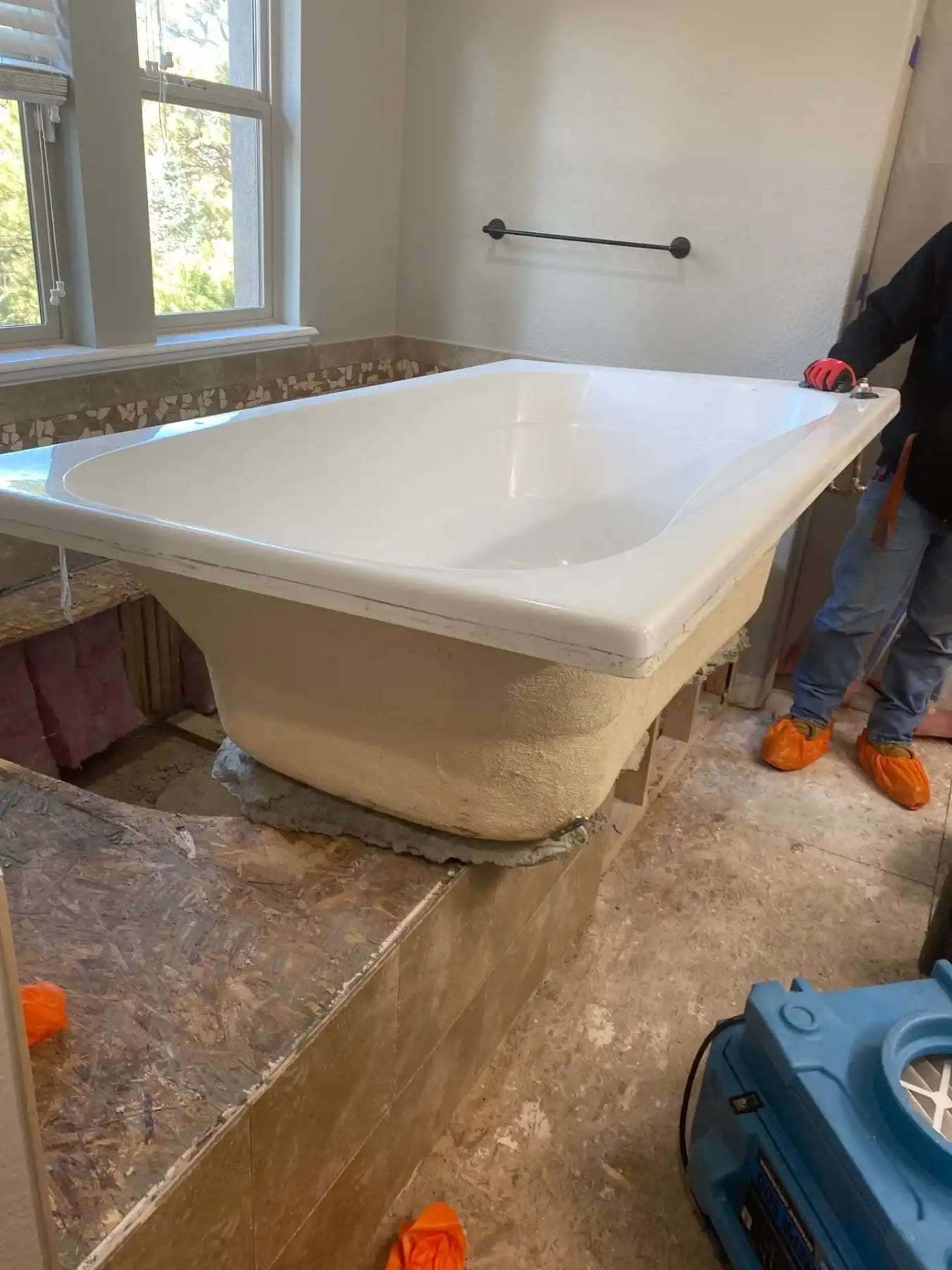 Bathtub with its surround removed and an air mover drying the subfloor