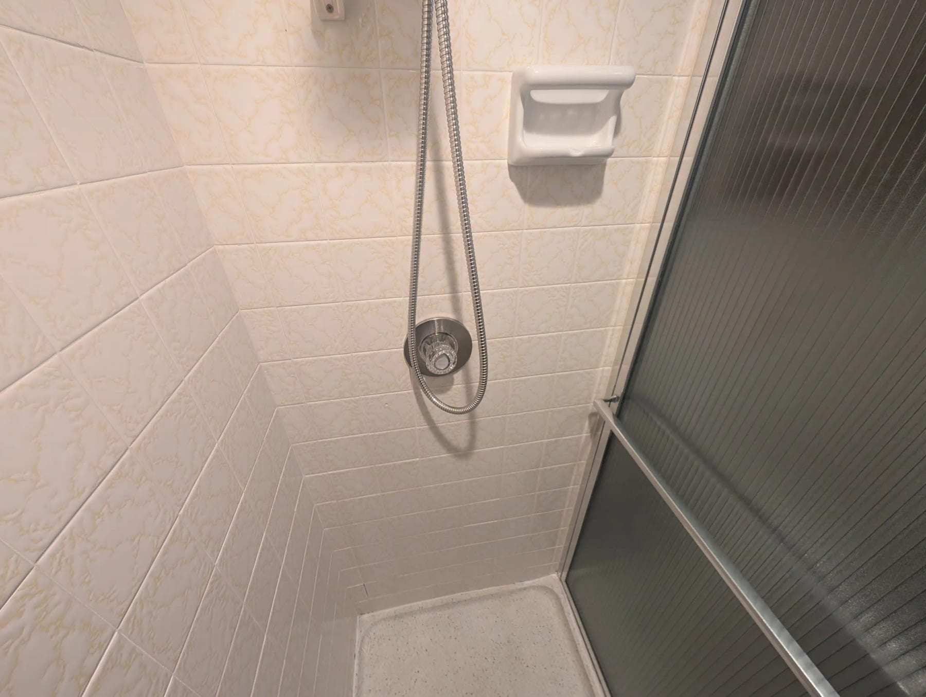 Shower stall with a handheld shower head and a soap dish