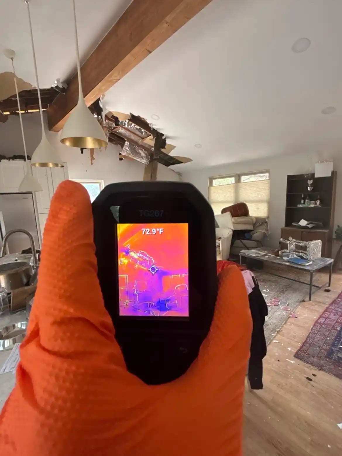 Thermal imaging camera held up toward a living room ceiling