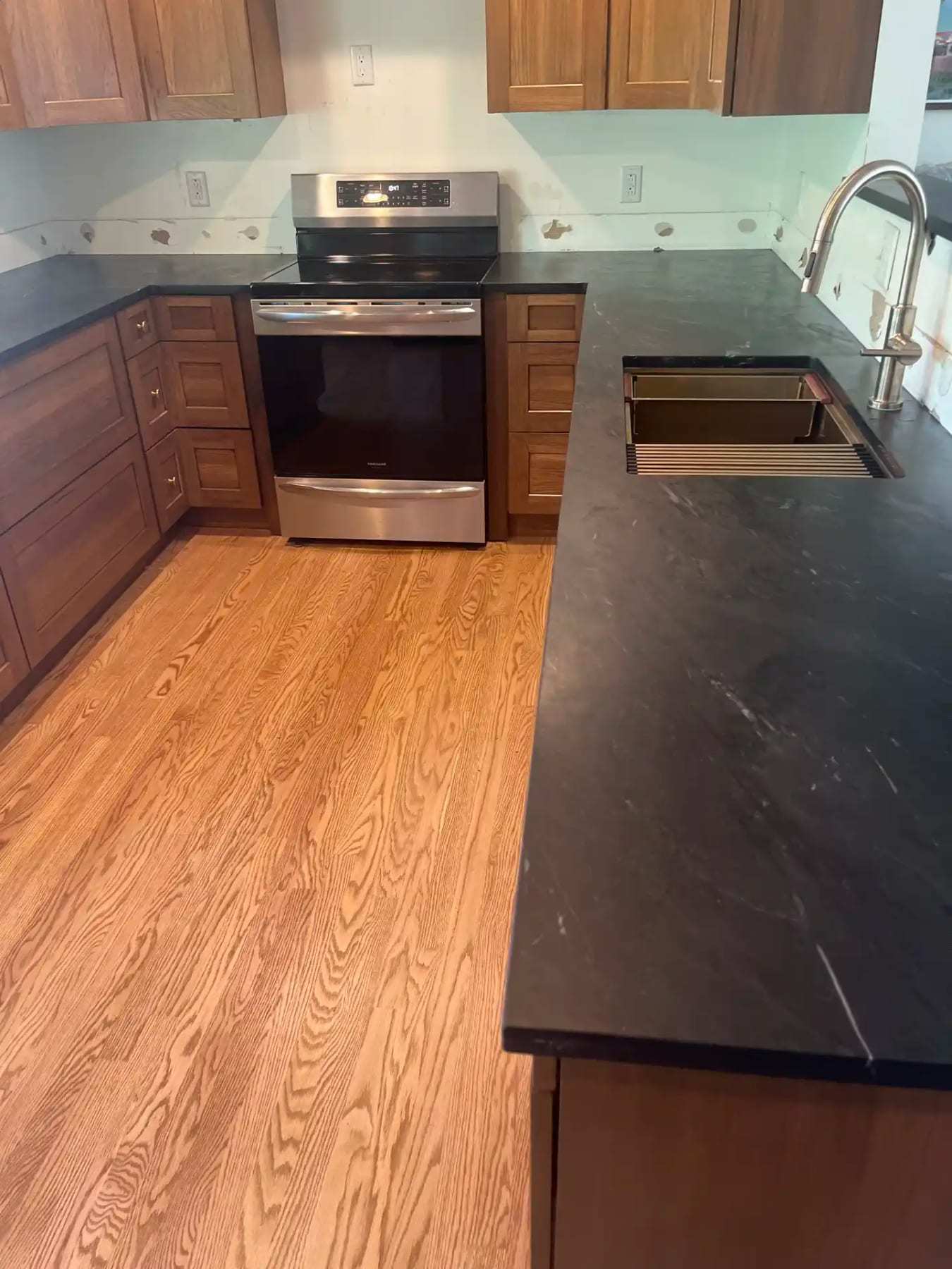 Finished kitchen with new oak flooring and dark countertops