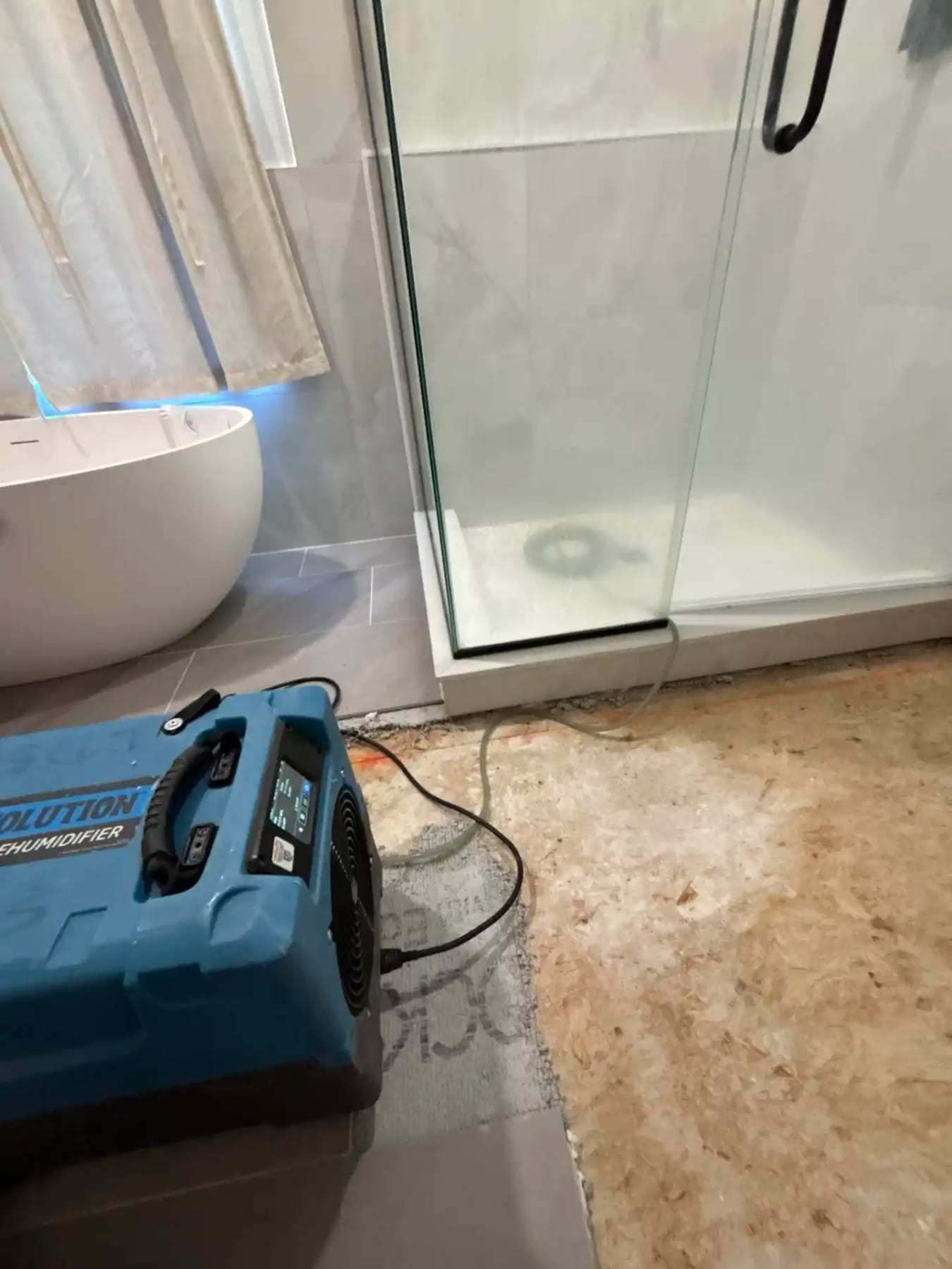 Bathroom with the tile removed to the subfloor and a dehumidifier running