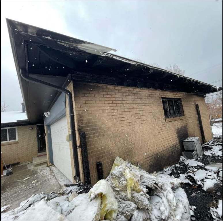 Fire-damaged brick house with debris in the snow