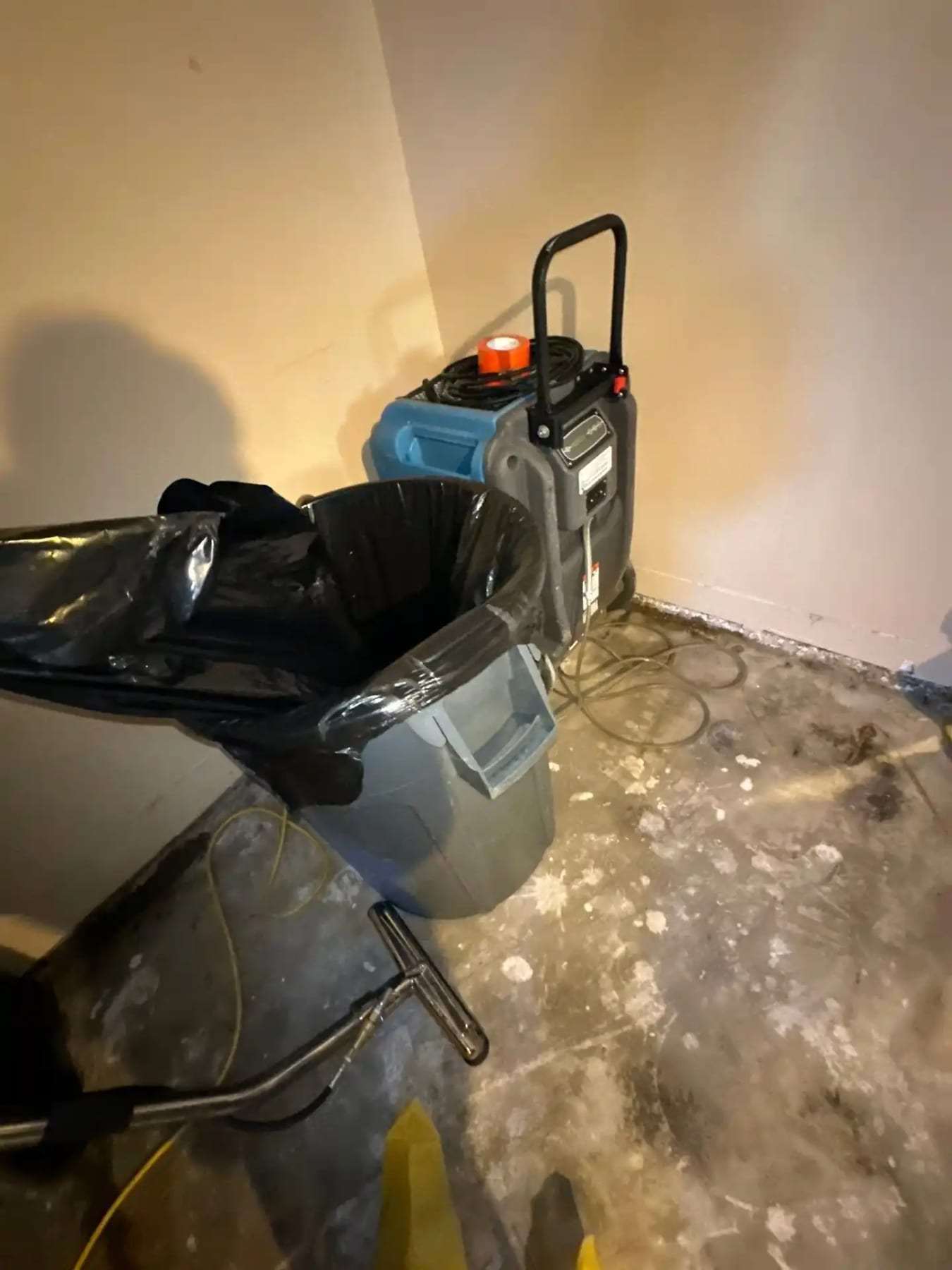 Air scrubber and a trash can on a wet basement floor
