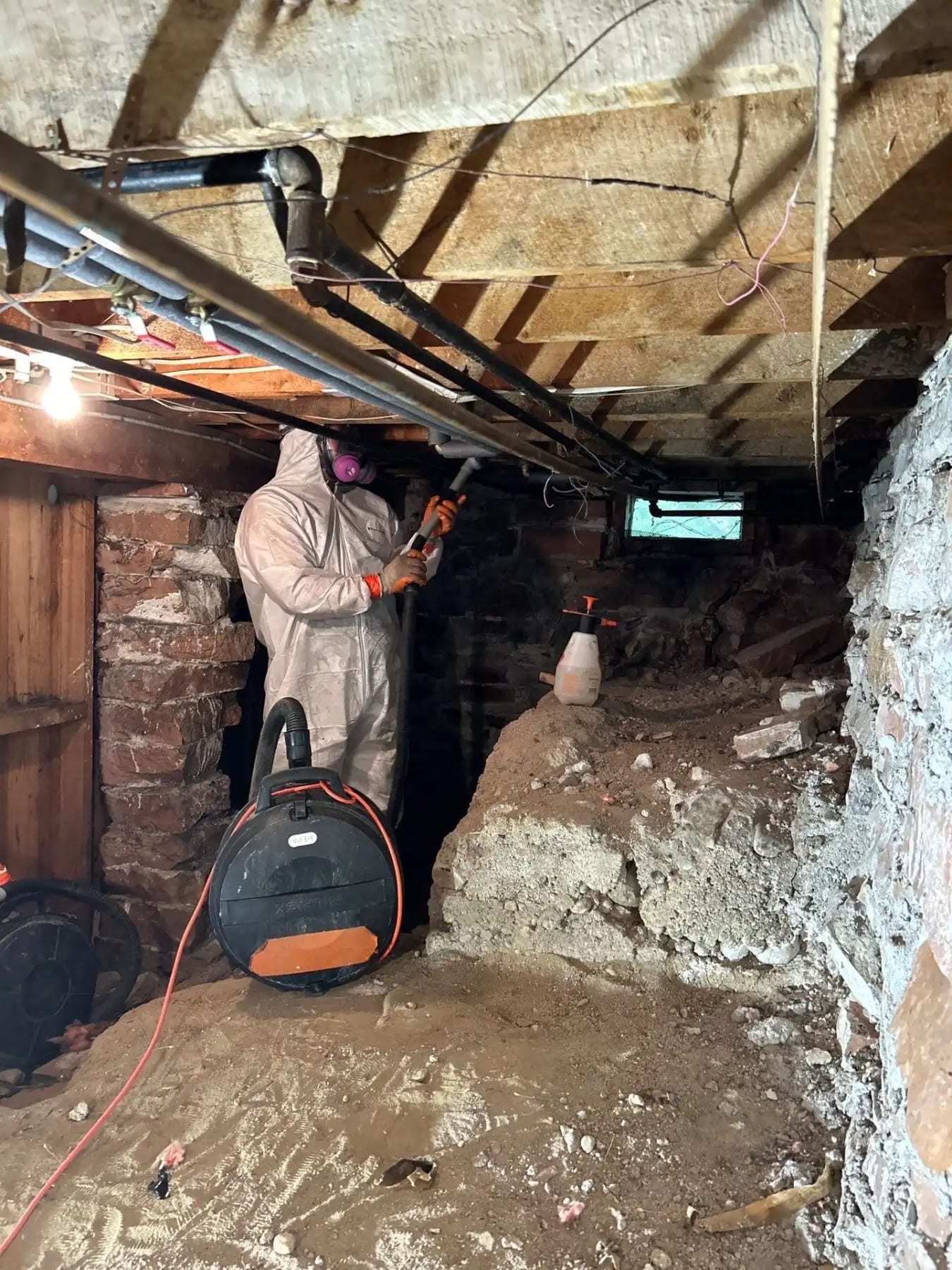 Technician with an air scrubber in a basement with stone foundation walls