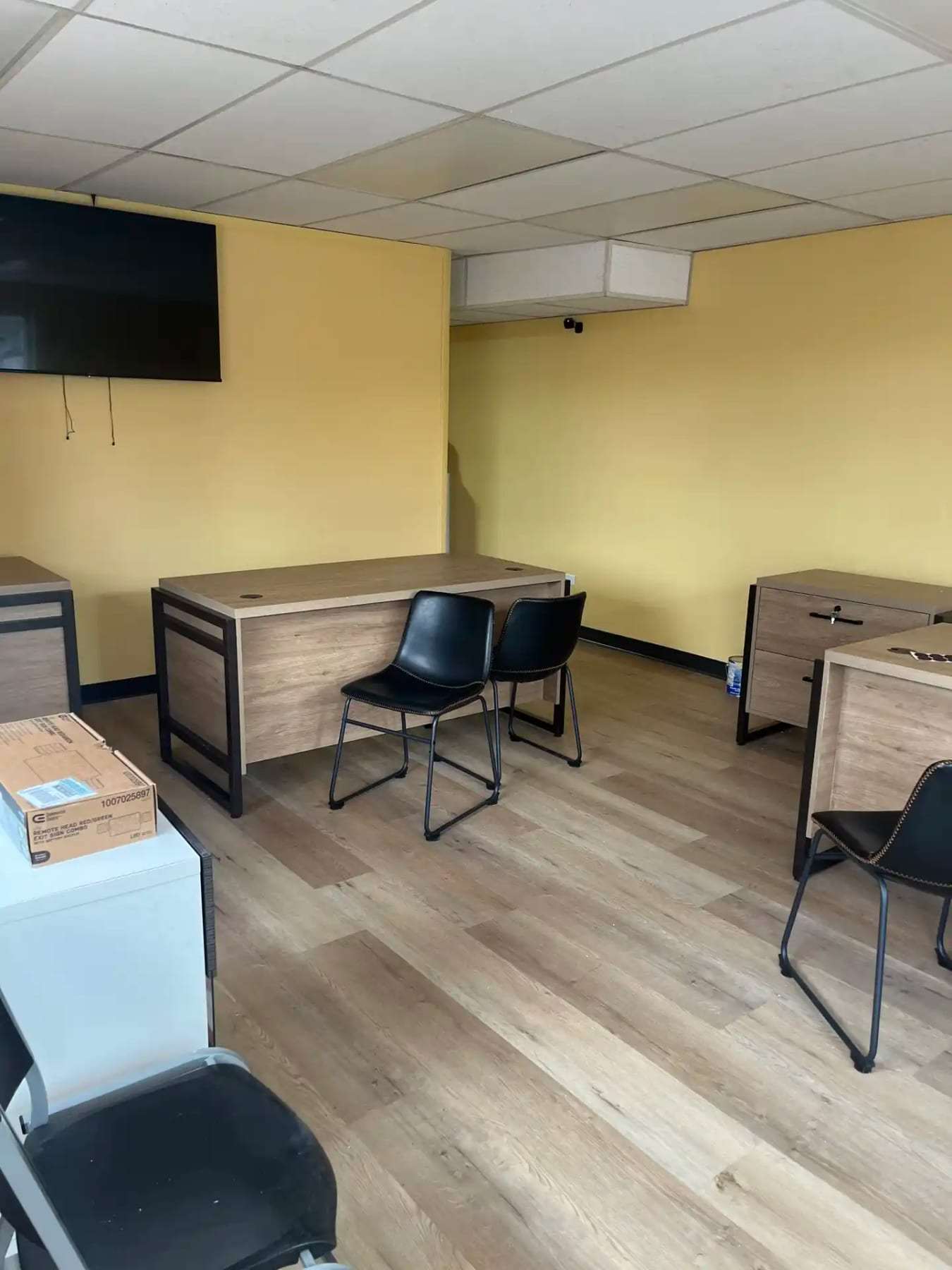 Small office with desks and chairs on plank flooring