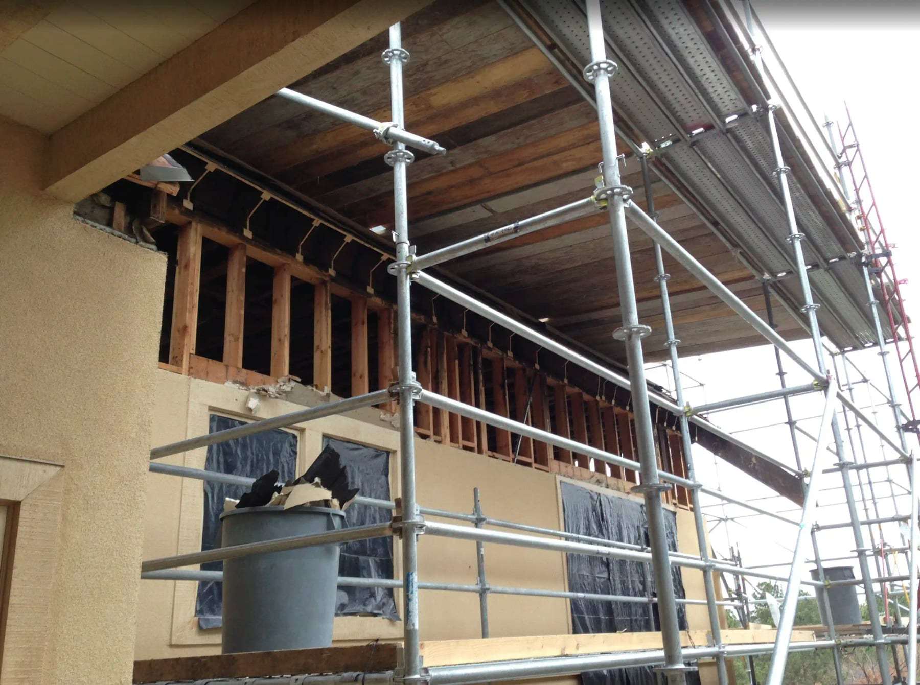Scaffolding against a house whose exterior wall has been opened for repair