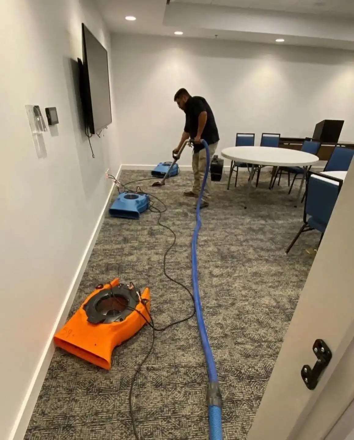 Technician extracting water from the carpet of a small conference room