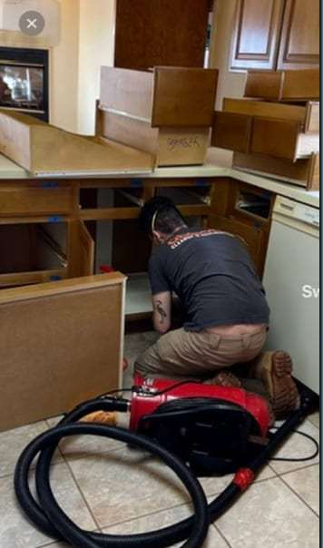 Technician extracting water where kitchen base cabinets were removed