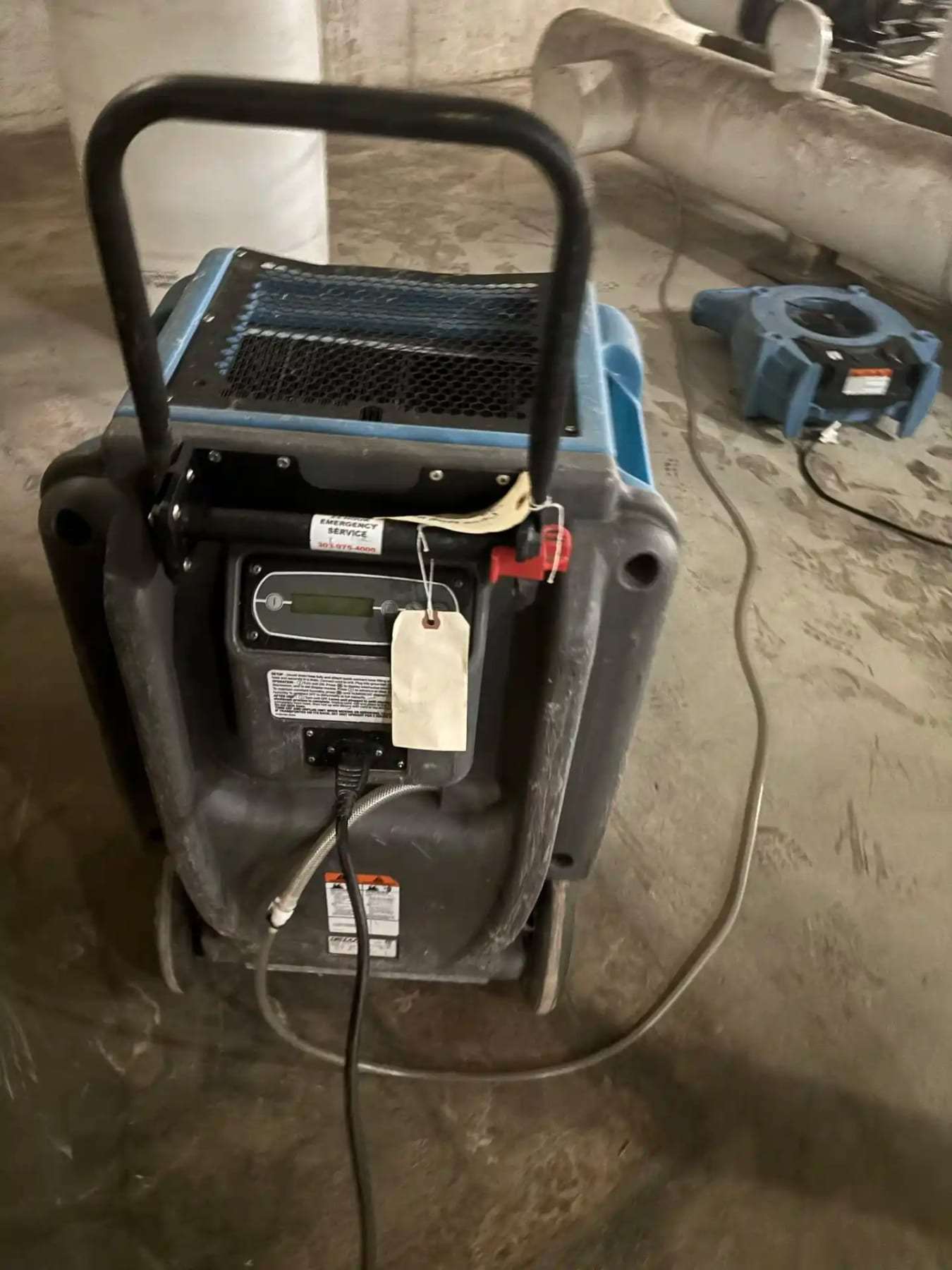 Submersible pump and an air mover on a wet concrete floor