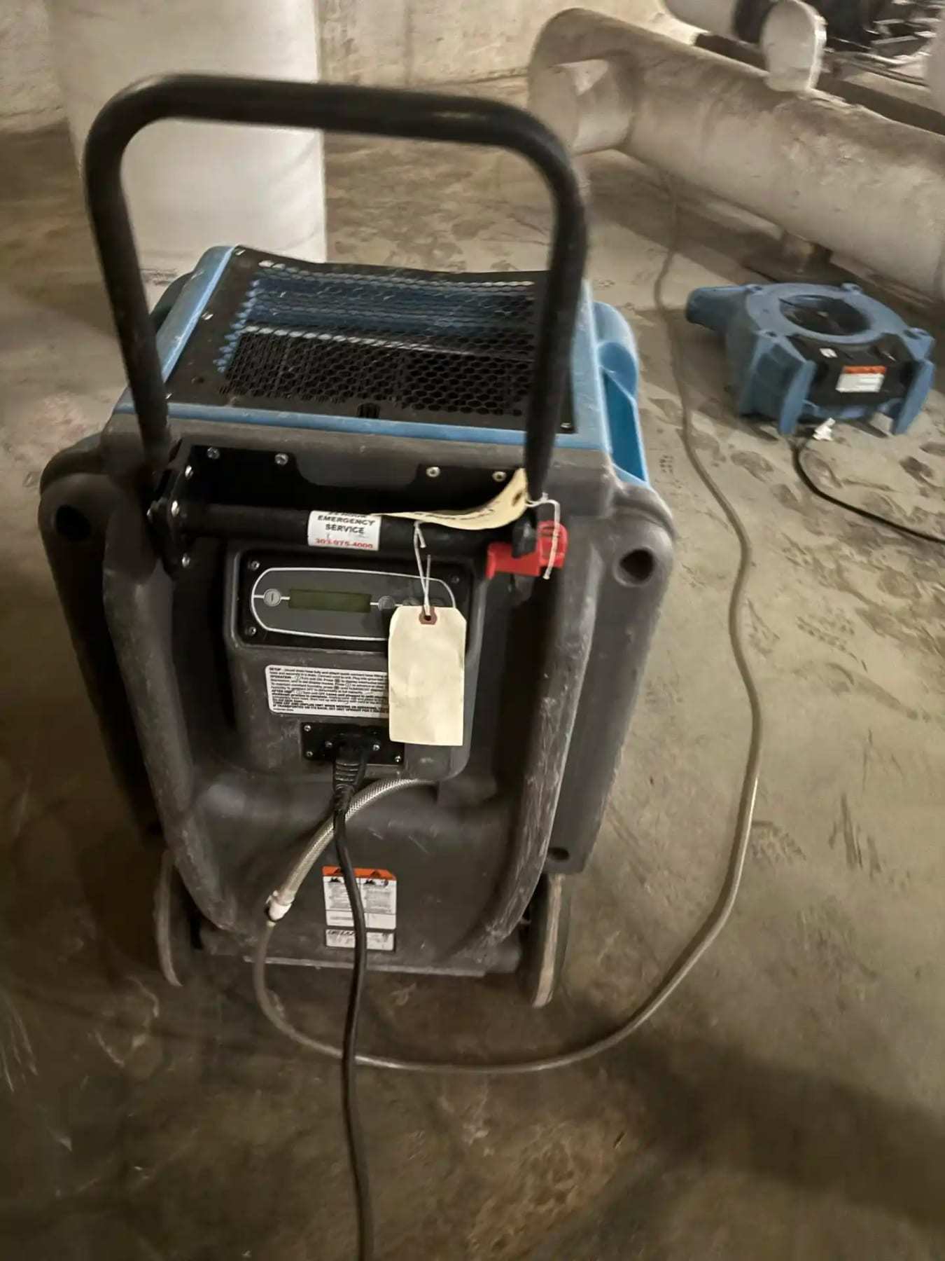 Submersible pump and an air mover on a wet concrete floor
