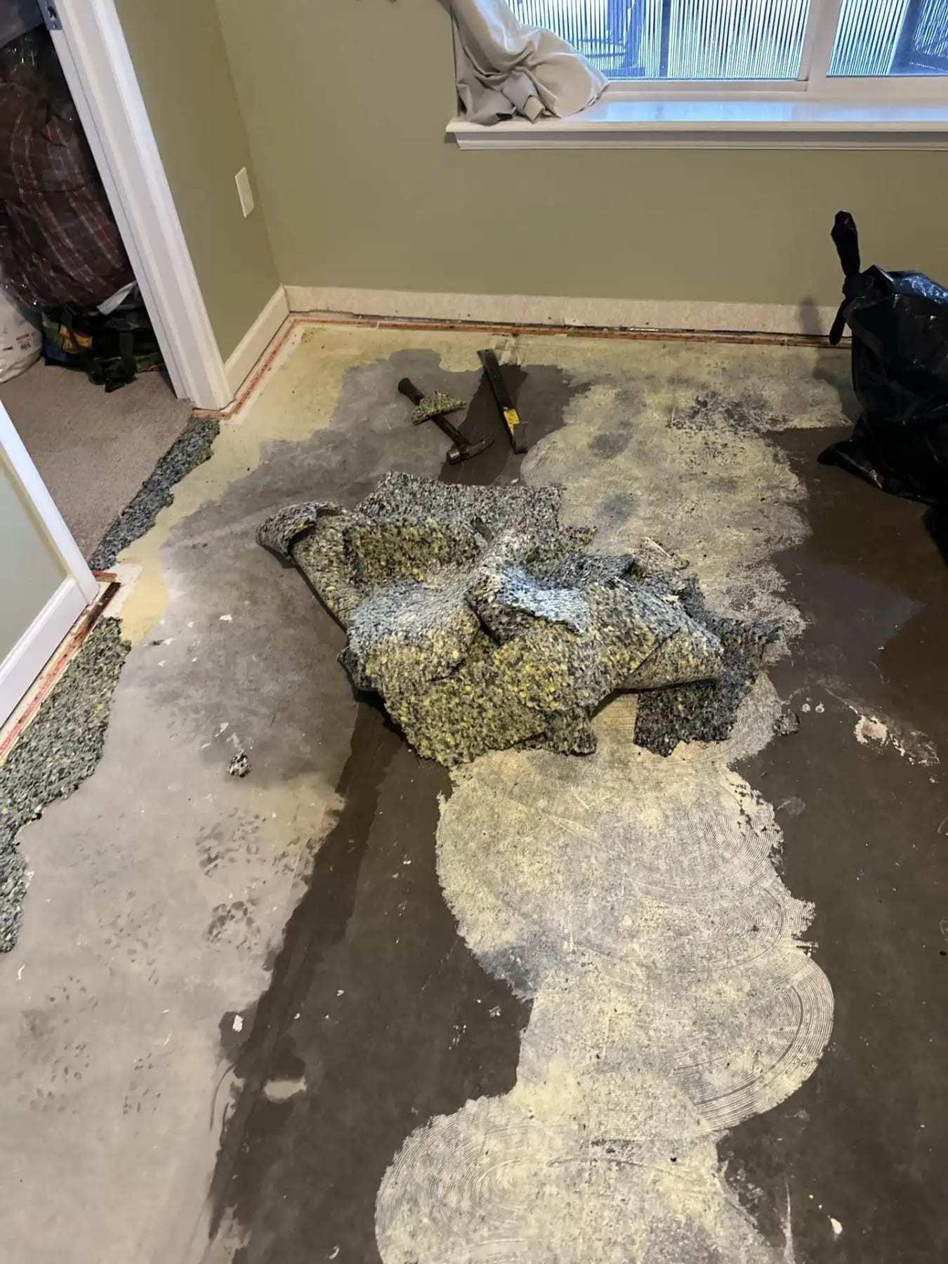 Wet carpet pad pulled up and piled on a concrete floor